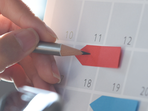 Hand pencilling in dates on a calendar
